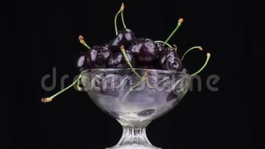 旋转一堆黑樱桃躺在玻璃花瓶里。